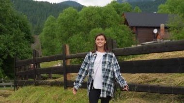 Genç, çekici, beyaz bir kadın çitin yanında duruyor.