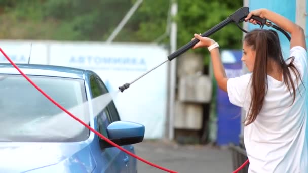 Jonge vrouw wassen blauwe auto bij carwash — Stockvideo