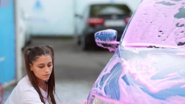 Молода блондинка миє свою машину — стокове відео