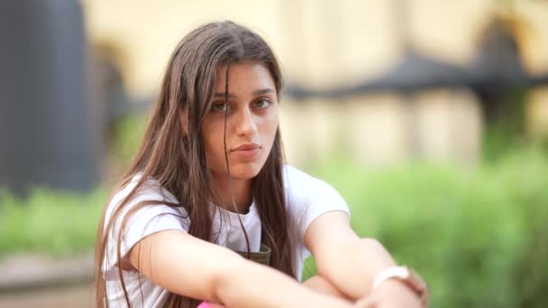 Young beautiful woman in the street stares serious at camera — Stock Video