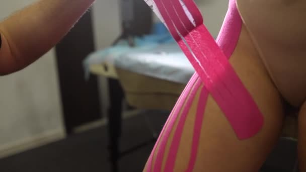 Fysiotherapeut die kinesio tape op vrouwelijke patiënt aanbrengt. — Stockvideo