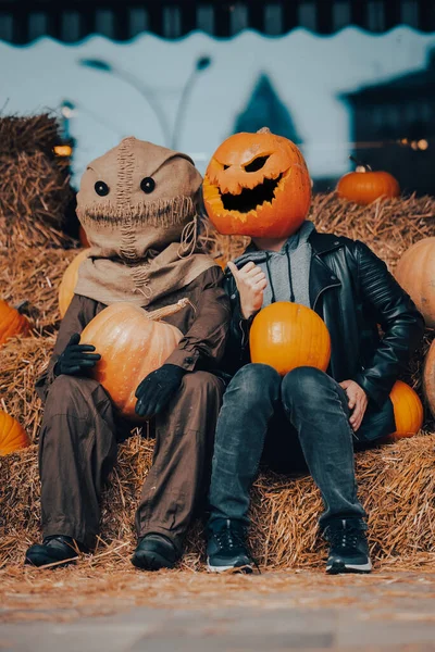 A guy with a pumpkin head sits next to a scarecrow — Stock Photo, Image