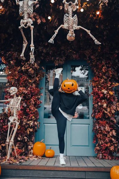 Girl with a pumpkin head posing at the door on the street — Stock Photo, Image