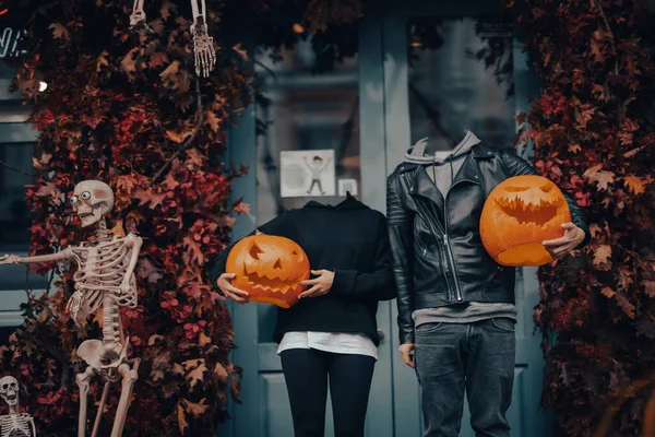 Headless couple holding pumpkin heads by the door on the street — Stock Photo, Image