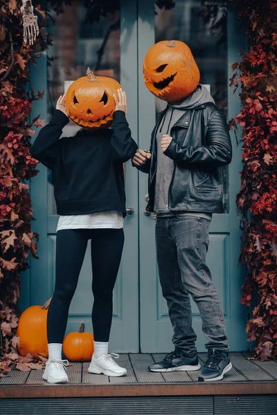 Couple with pumpkin heads posing on camu at the building — Stock Photo, Image