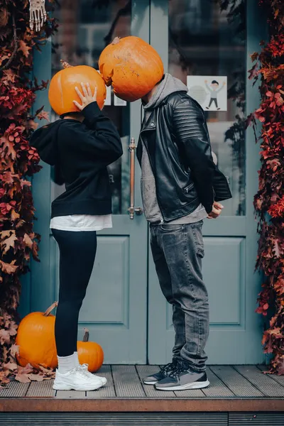 Couple with pumpkin heads posing on camu at the building — Stock Photo, Image