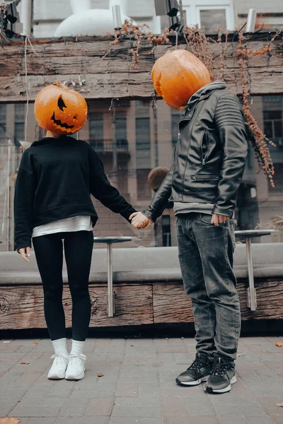 A guy and a girl with a pumpkin heads. Couple holding hands — Stock Photo, Image