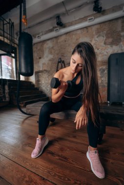 Genç bir kadın tek koluyla kaslarını şişiriyor..