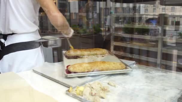 Un hombre prepara un strudel de manzana para la venta. Manchado con un pincel — Vídeo de stock