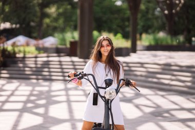 Genç, güzel bir kadın ve elektrikli scooter, ekolojik nakliye aracı.