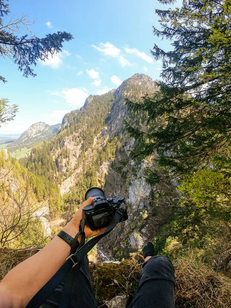 En fotograf observerar med kameran i handen från toppen av ett berg. — Stockfoto