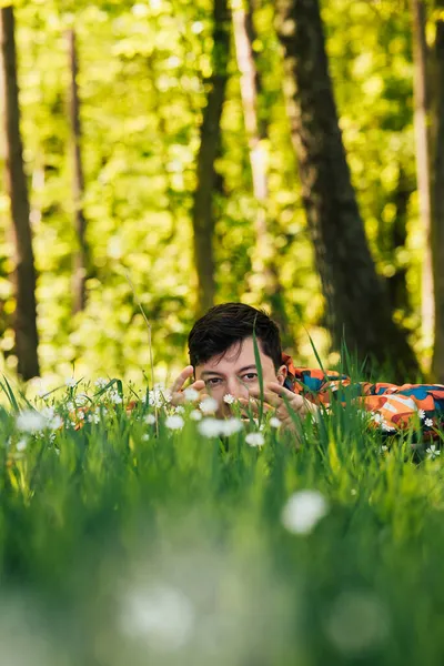 Jovem escondido na grama verde — Fotografia de Stock