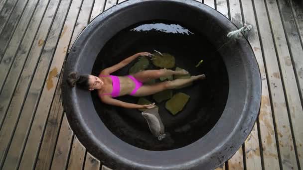 Frau entspannt sich im runden Außenbad. Biologische Hautpflege im heißen Bad — Stockvideo