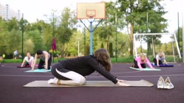 Motivasyonlu yoga hocası dışarıda paspas egzersizi yapıyor.