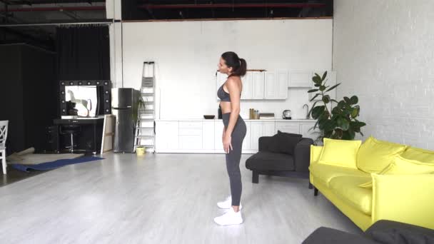 Όμορφη νεαρή γυναίκα κάνει κοιλιακές ασκήσεις στο δωμάτιο — Αρχείο Βίντεο