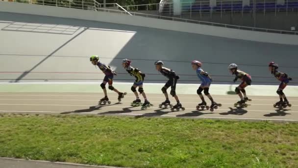 Gyermekek gyakorló ruhák és sisakok lovagolni görgők a kerékpár pályán — Stock videók