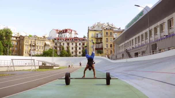Muskulös kille går på sina händer på idrottsplats — Stockvideo