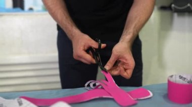 Fizyoterapist hazırlar ve kinesio taping keser.
