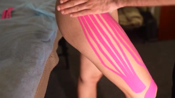 Physiotherapeutin klebt Kinesiotape auf Patientin. — Stockvideo