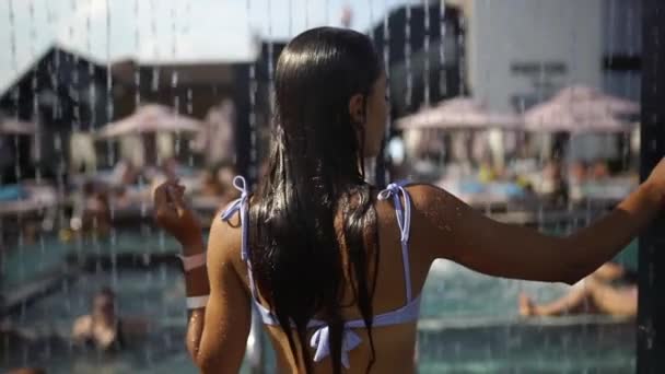 リゾートビーチで水の下でシャワーを浴びている美しい女の子. — ストック動画
