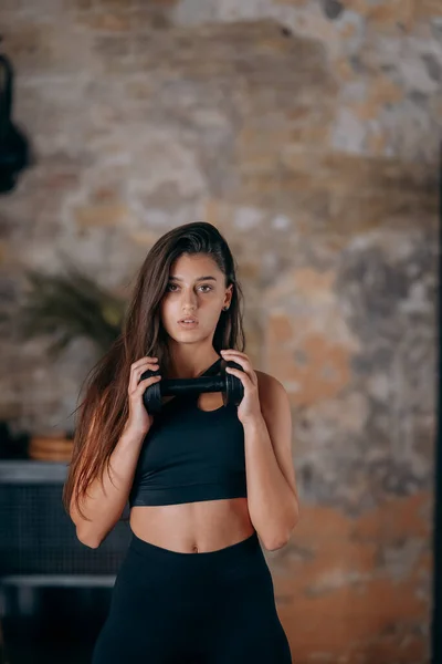 Mujer joven posando ante la cámara con mancuernas en las manos. — Foto de Stock