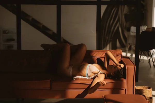 Красива жінка в нижній білизні розслабляється на дивані — стокове фото