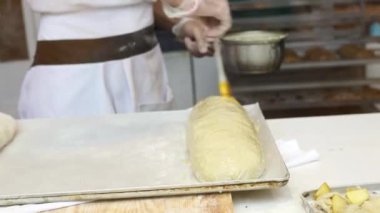 Bir adam satılık elmalı turta hazırlar. Fırçayla kaplanarak