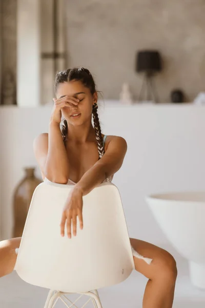 Meisje in lingerie zit op een stoel met gesloten ogen — Stockfoto
