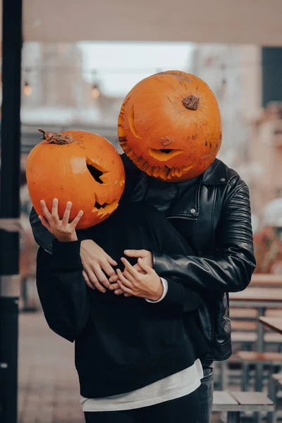 A guy and a girl with a pumpkin heads posing on the street — Stock Photo, Image