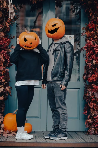 Couple with pumpkin heads posing on camu at the building — Stock Photo, Image