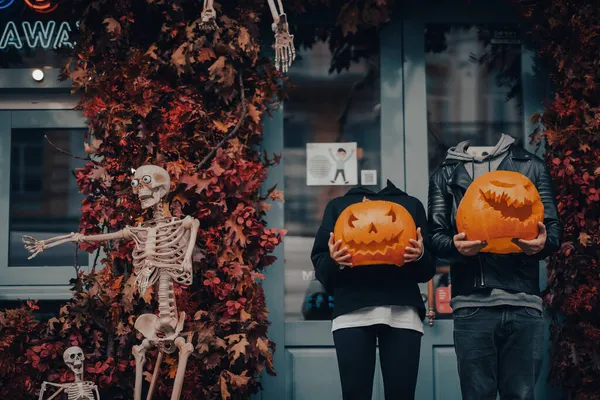 Headless couple holding pumpkin heads by the door on the street — Stock Photo, Image