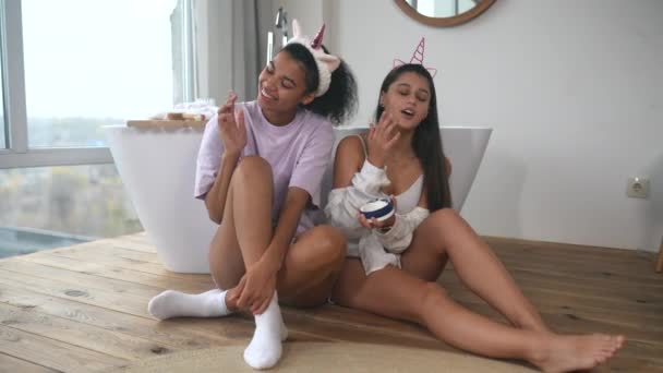 Dvě přítelkyně na podlaze koupelny mluví a starají se o pokožku — Stock video