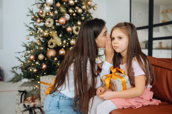 Junge Mutter beruhigt ihre traurige kleine Tochter sitzend — Stockfoto