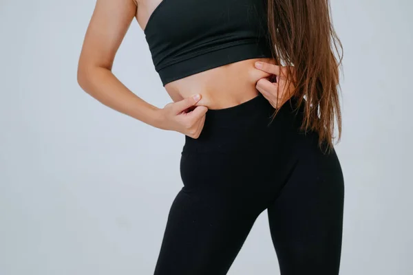 Young woman showing fat on her belly over white background. — Stock Photo, Image