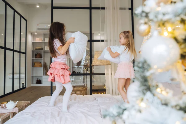 Дві маленькі дівчата грають з подушками в спальні — стокове фото