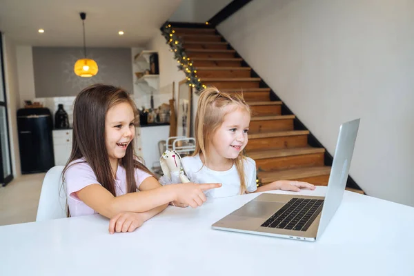 식탁에 앉아서 노트북에서 놀고 있는 두 어린 소녀 — 스톡 사진