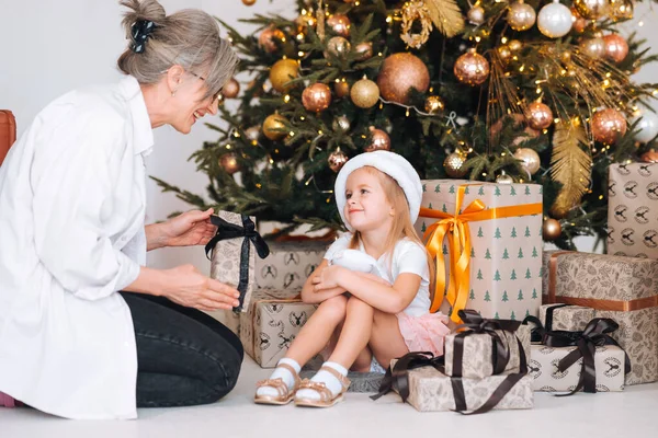 Glückliche Großmutter macht aufgeregter Enkelin ein Weihnachtsgeschenk. — Stockfoto