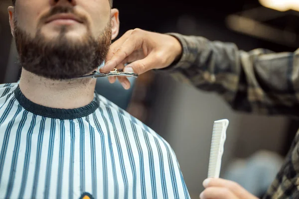 Hairdresser doing haircut of beard using comb and scissors — Stock Photo, Image