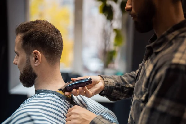 Maestro en barbería hace mens corte de pelo con cortador de pelo — Foto de Stock