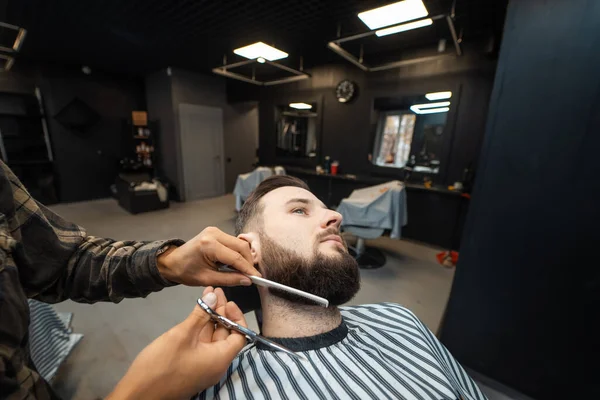 Cabeleireiro fazendo corte de cabelo de barba usando pente e tesoura — Fotografia de Stock