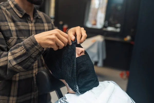 Barbeiro preparando cara de homem para barbear com toalha quente na barbearia — Fotografia de Stock