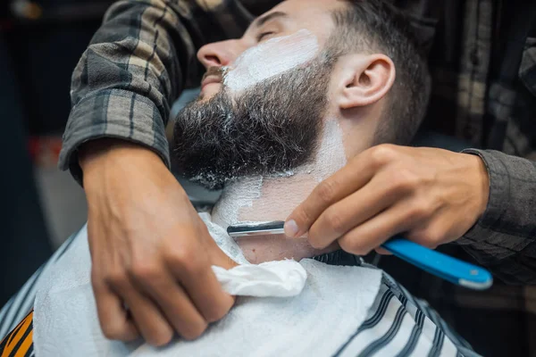 Jovem barbudo homem chegando barbeado por cabeleireiro no barbearia — Fotografia de Stock