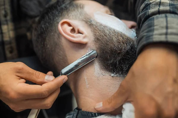 Jovem barbudo homem chegando barbeado por cabeleireiro no barbearia — Fotografia de Stock