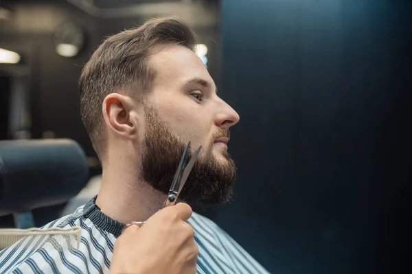 Cabeleireiro fazendo corte de cabelo de barba usando pente e tesoura — Fotografia de Stock