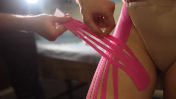 여성 환자에게 크레 노시오 테이프를 사용하는 물리 치료사. — 비디오