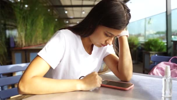 Kafede oturup mesaj yazan akıllı telefonu kullanan güzel bir kadın. — Stok video