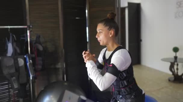Entrenamiento en EMS. Chica haciendo ejercicios en un traje con cables. — Vídeos de Stock