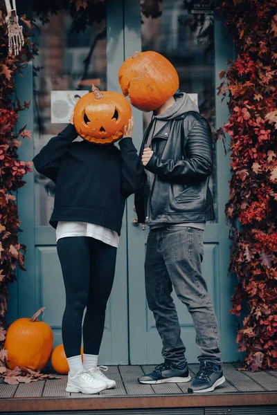 Pareja con cabezas de calabaza posando en camu en el edificio — Foto de Stock