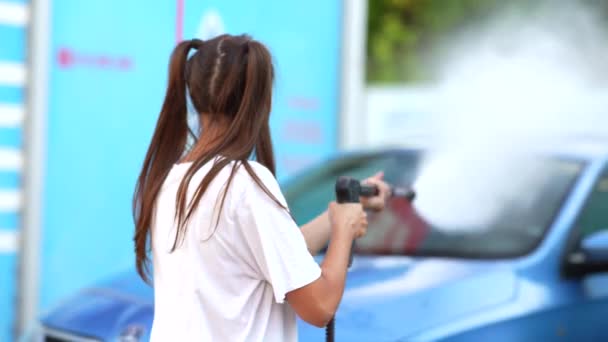 Junge Frau wäscht blaues Auto in Waschanlage — Stockvideo