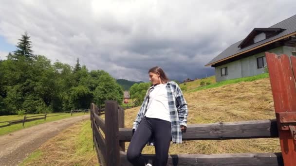 Μια νεαρή ελκυστική λευκή γυναίκα κάθεται σε ένα φράχτη — Αρχείο Βίντεο